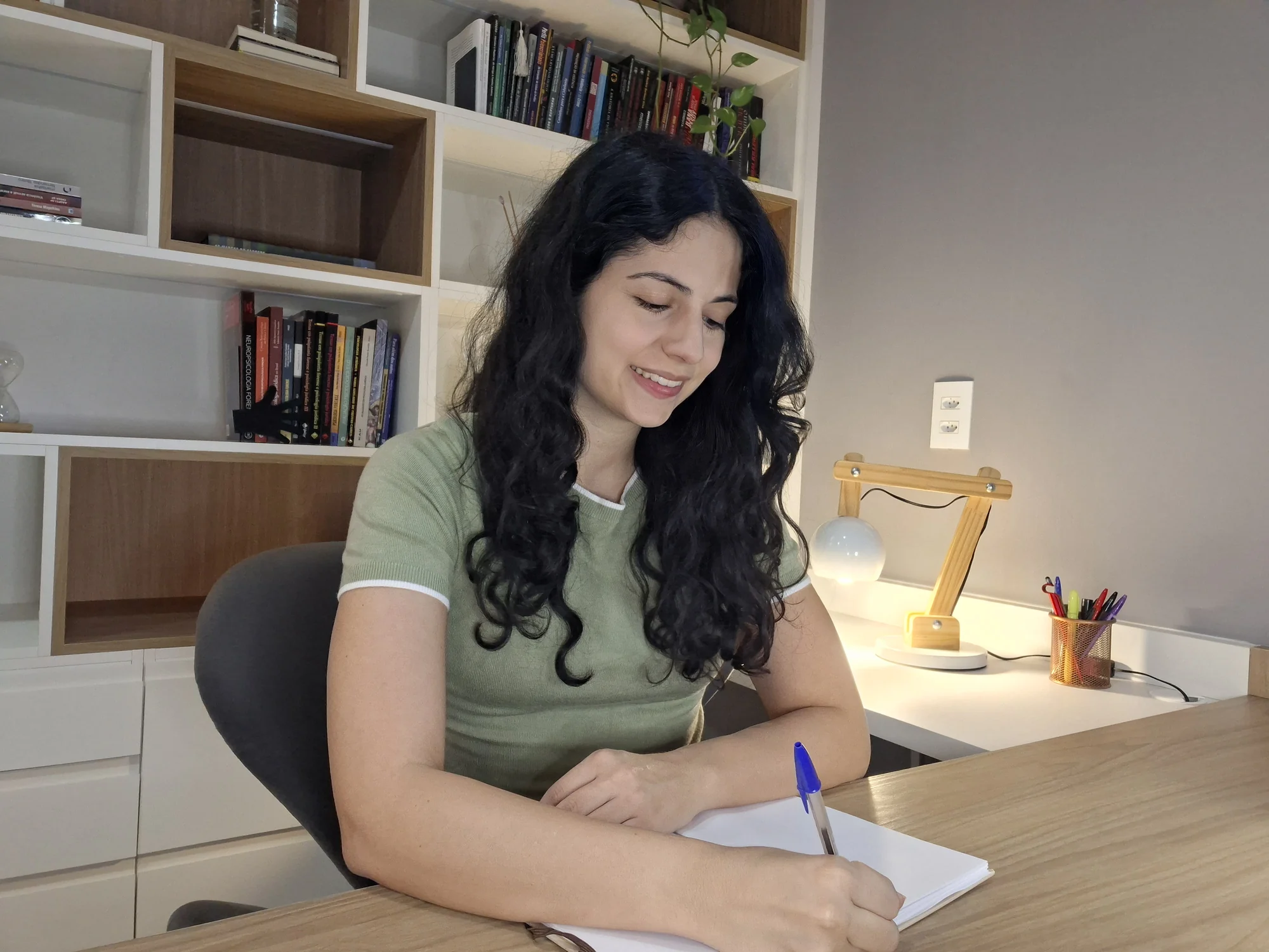 Milena escrevendo durante um momento de estudo em seu consultório